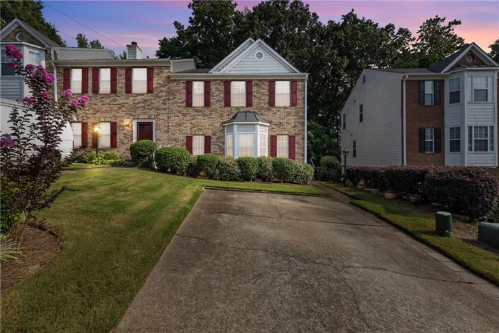 Brick facade residence with red shutters, a bay window, and an attached garage