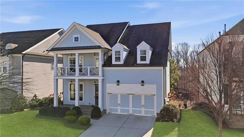 View of front of home featuring a front yard, concrete driveway, a garage, a balcony, and roof with shingles