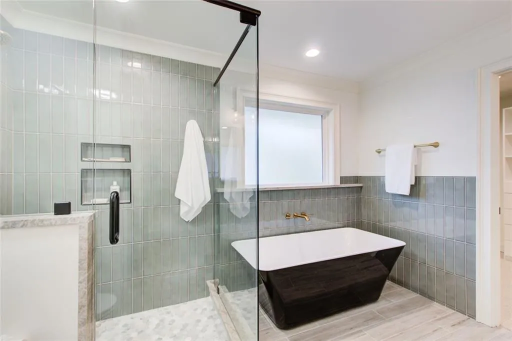 Custom marble shower & sleek black soaking tub plus a custom linen closet in the primary bath