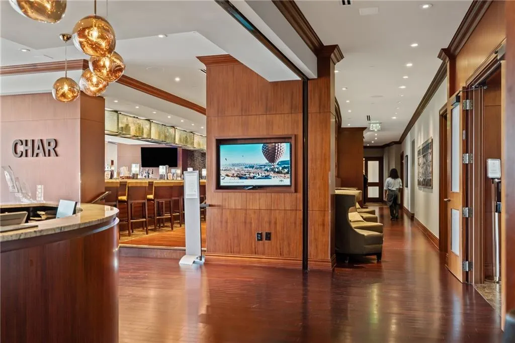 Reception area with ornamental molding, wood walls, a community bar, and recessed lighting