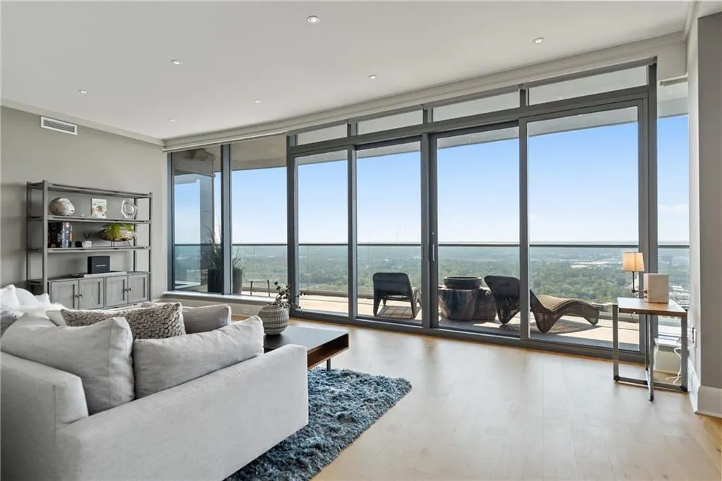 Living area with a wall of windows, light wood finished floors, and recessed lighting