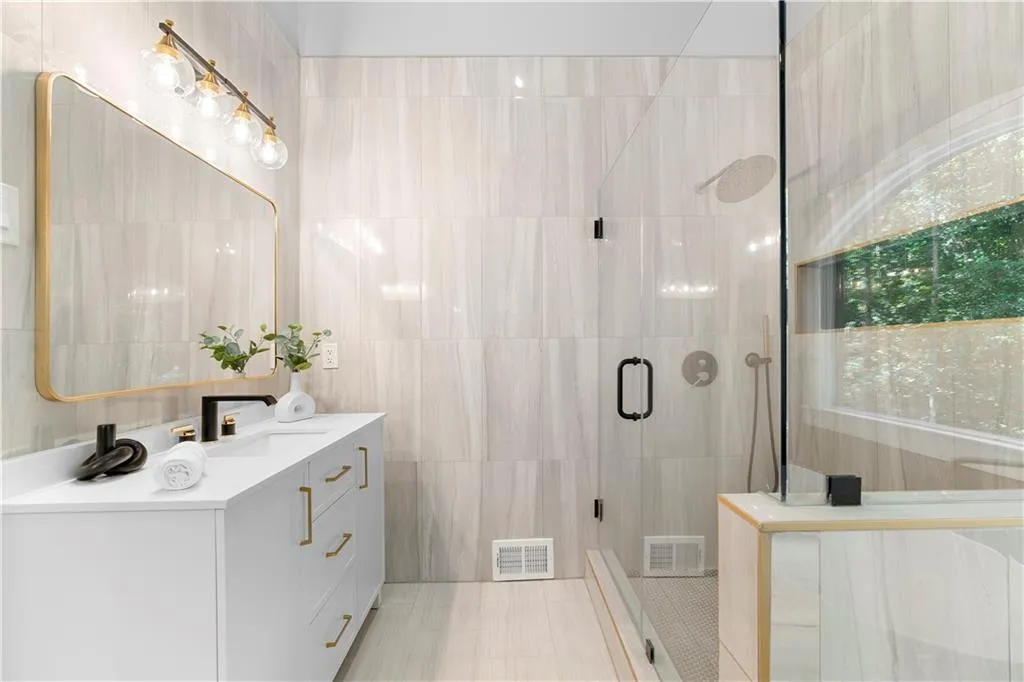 Full bathroom with tile walls, vanity, and a stall shower