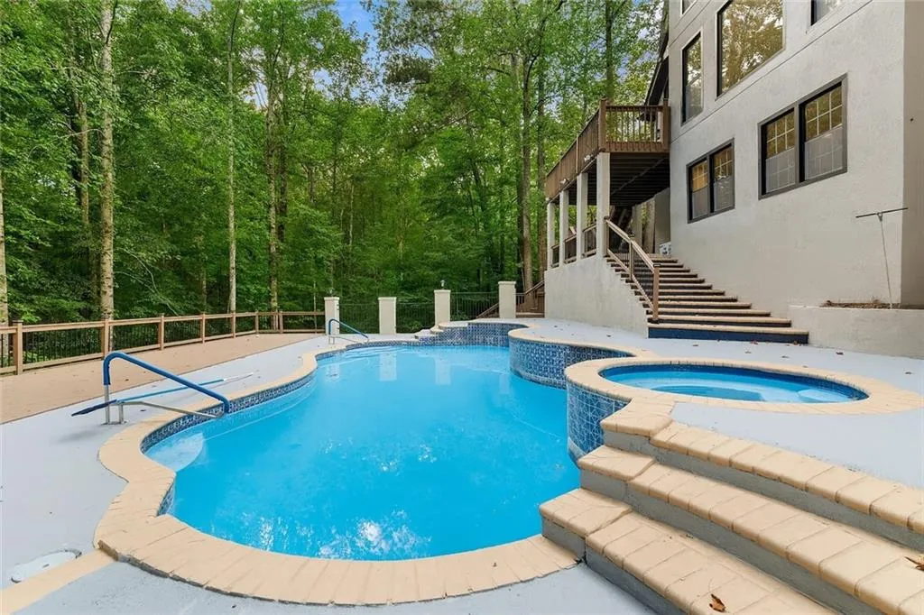 View of pool featuring stairway, a pool with connected hot tub, and a deck