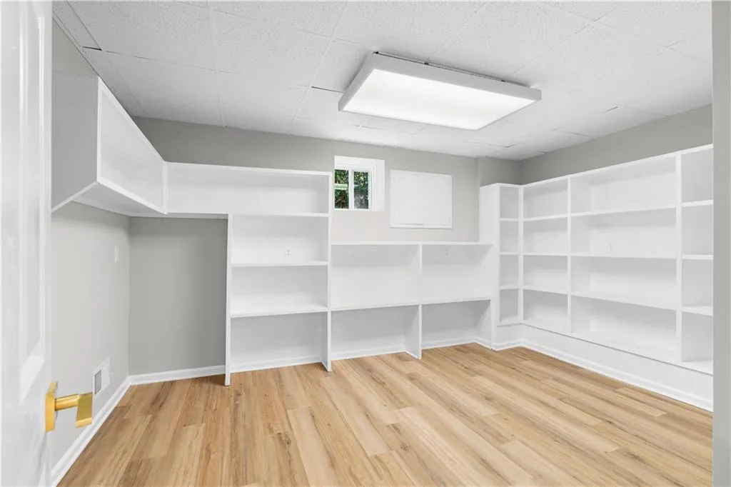 Spacious closet with light wood-type flooring and a drop ceiling