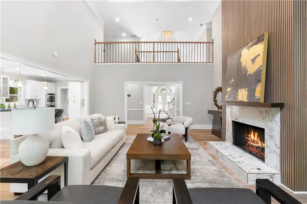 Living room with light wood finished floors, ornamental molding, a premium fireplace, recessed lighting, and a high ceiling