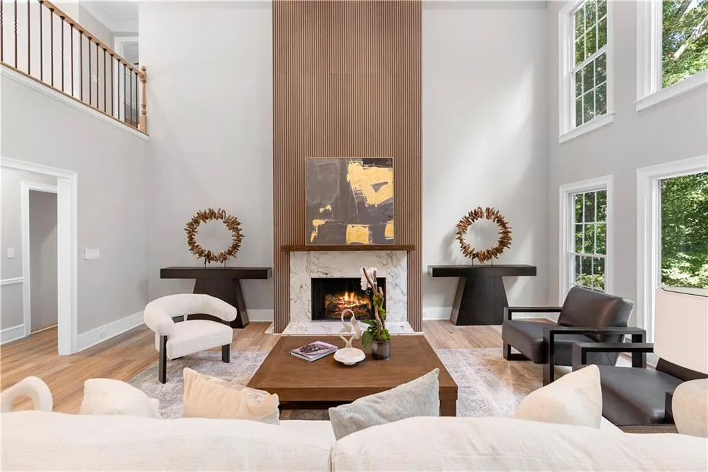 Living room with a towering ceiling, healthy amount of natural light, light wood finished floors, and a fireplace