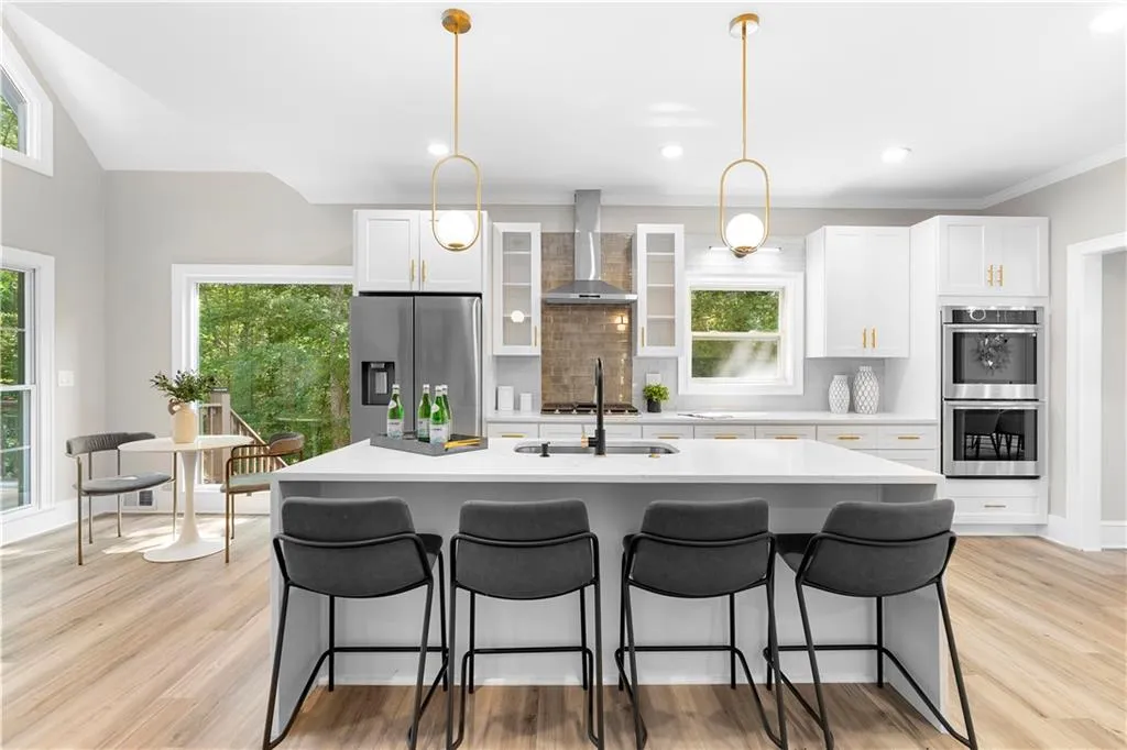 Kitchen featuring backsplash, appliances with stainless steel finishes, a center island with sink, light countertops, and ornamental molding