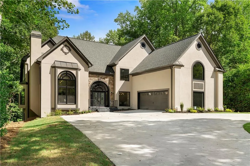 French provincial home featuring stucco siding, a chimney, roof with shingles, and stone siding