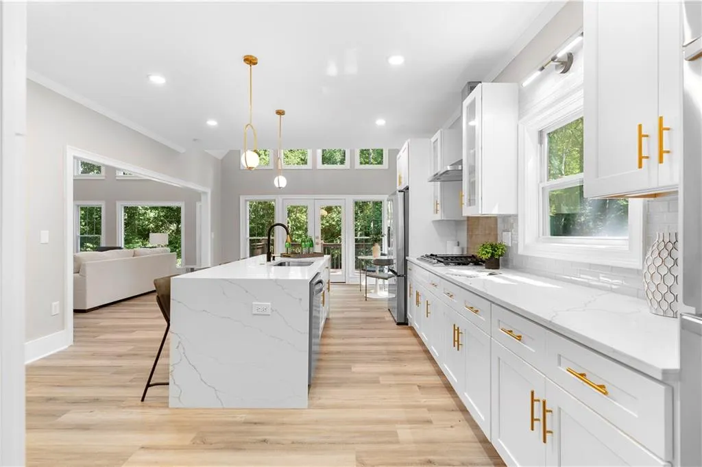 Kitchen with french doors, a kitchen island with sink, ornamental molding, decorative backsplash, and light wood-style flooring