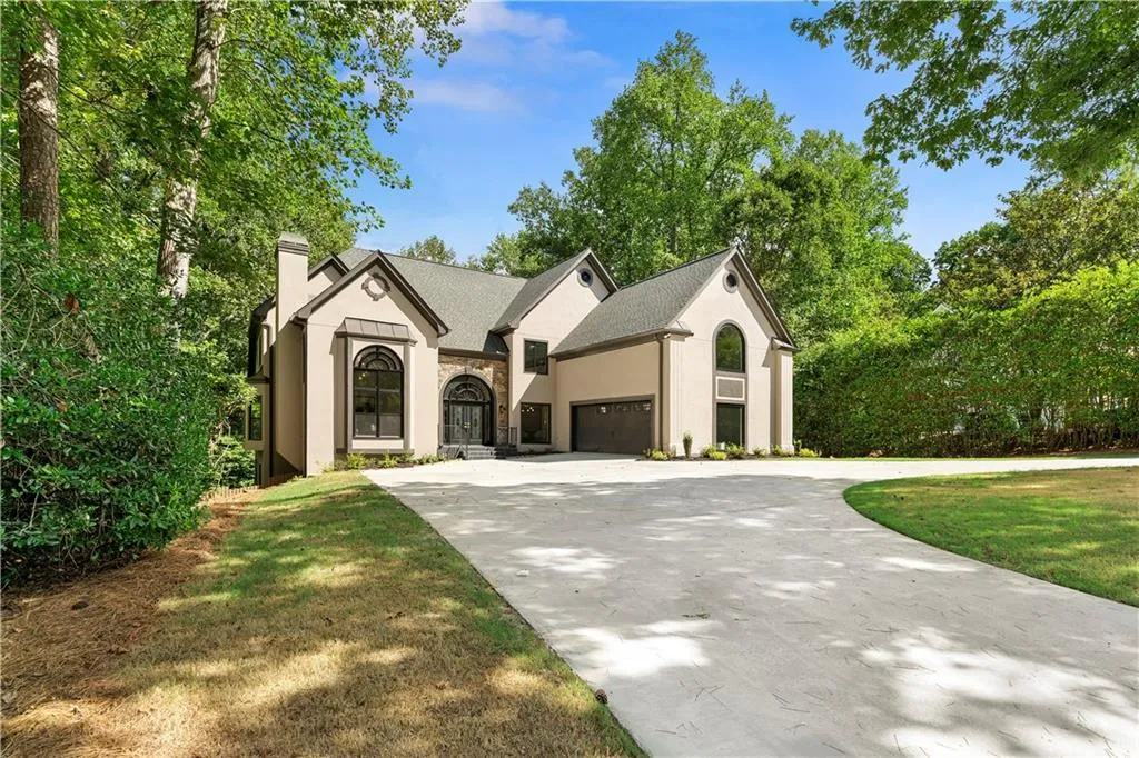 French provincial home featuring concrete driveway, a chimney, a garage, stone siding, and stucco siding