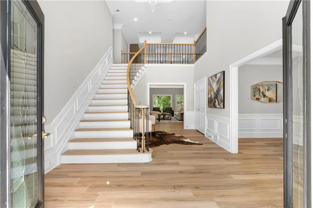 Foyer featuring wood finished floors, stairway, ornamental molding, a decorative wall, and a wainscoted wall