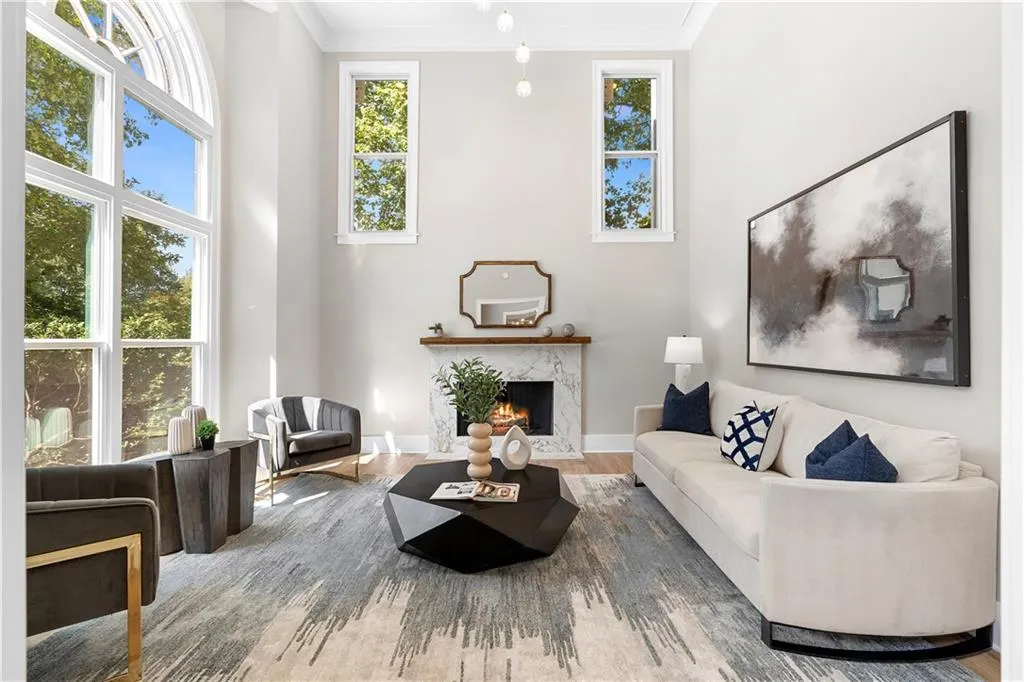 Living room with ornamental molding, a high end fireplace, wood finished floors, and a high ceiling