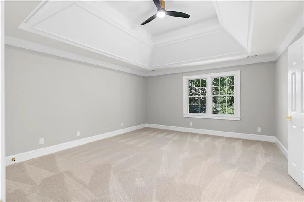 Empty room featuring light carpet, ceiling fan, and crown molding