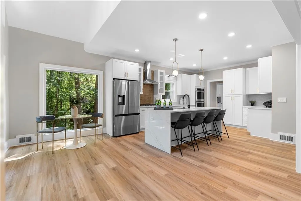 Kitchen featuring tasteful backsplash, appliances with stainless steel finishes, a kitchen breakfast bar, light wood-type flooring, and an island with sink
