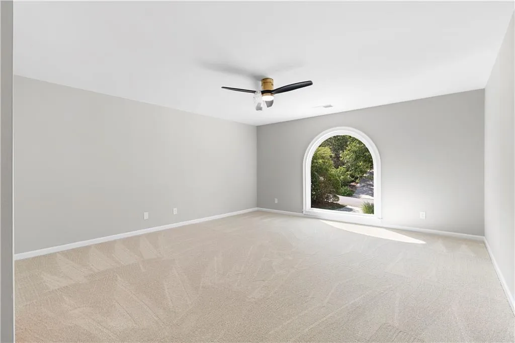 Empty room with light colored carpet and a ceiling fan