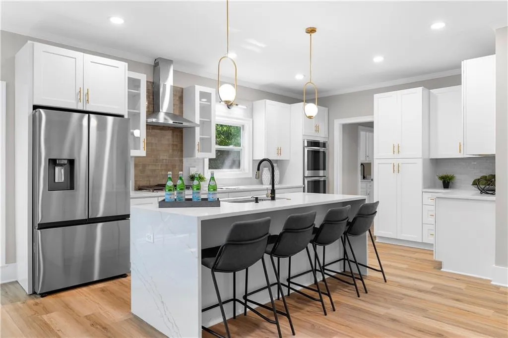 Kitchen with backsplash, stainless steel appliances, a center island with sink, ornamental molding, and recessed lighting