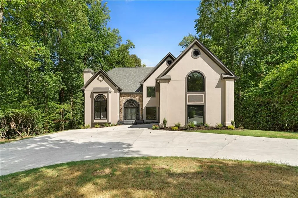 View of front of house featuring stucco siding, a chimney, stone siding, and a front yard
