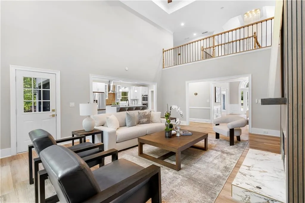 Living room with light wood finished floors, a high ceiling, and recessed lighting
