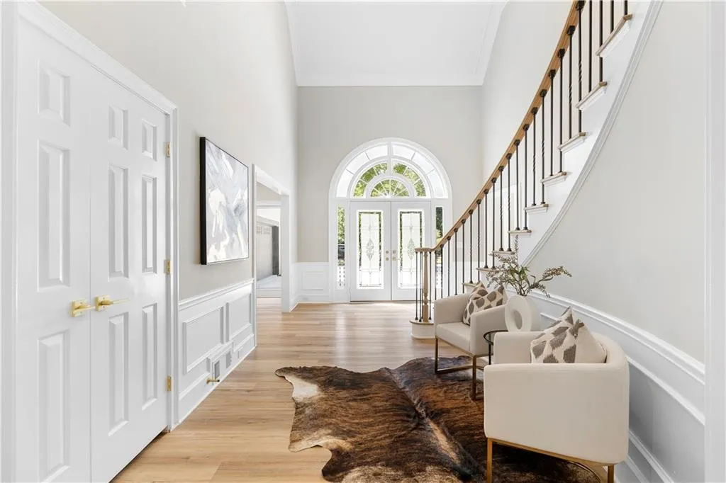 Entryway featuring a decorative wall, wainscoting, light wood-style floors, ornamental molding, and stairs