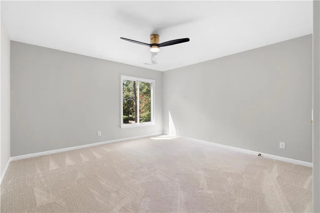 Carpeted spare room with a ceiling fan and baseboards