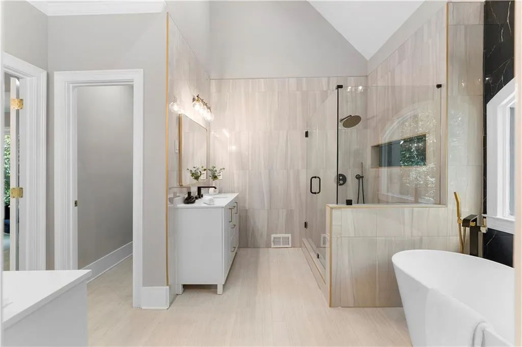 Full bath with vanity, a stall shower, tile walls, a freestanding tub, and vaulted ceiling