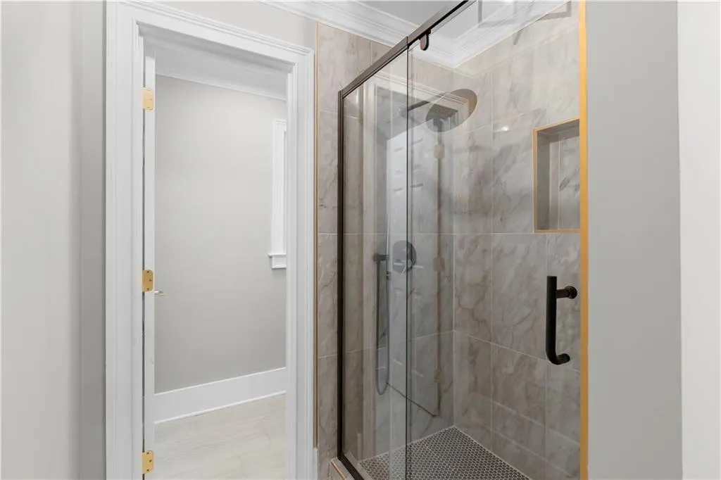 Full bath with ornamental molding and a stall shower