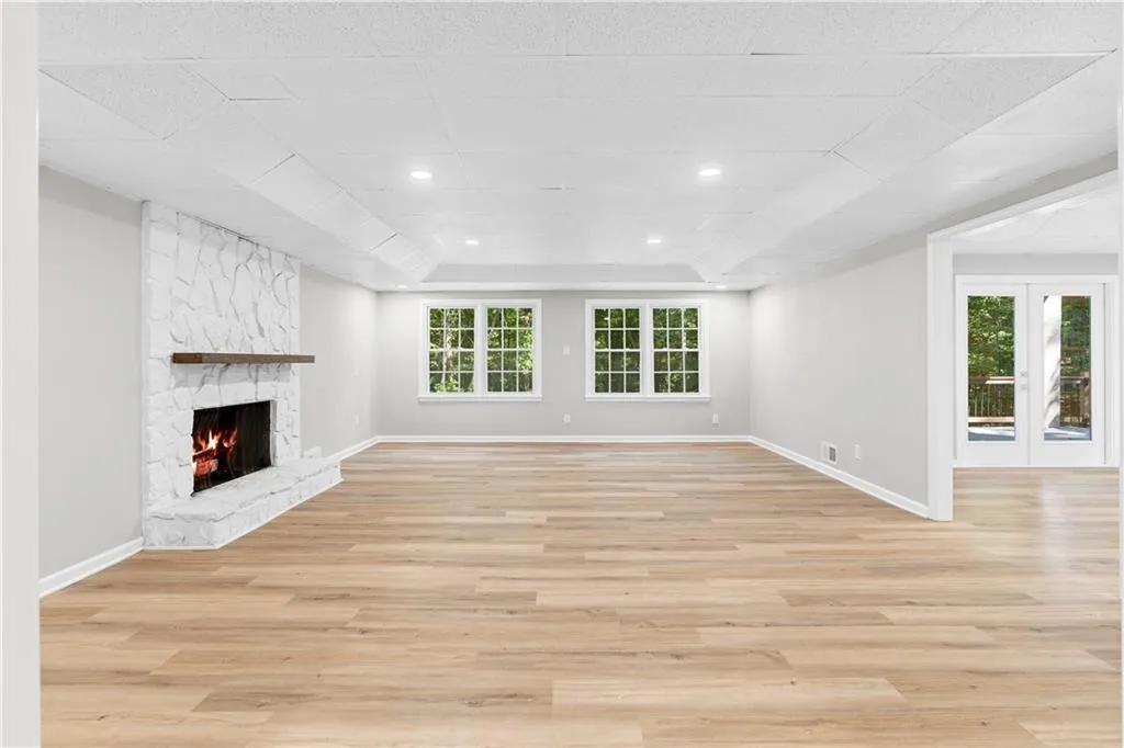 Unfurnished living room featuring light wood-style floors, healthy amount of natural light, a premium fireplace, a tray ceiling, and recessed lighting