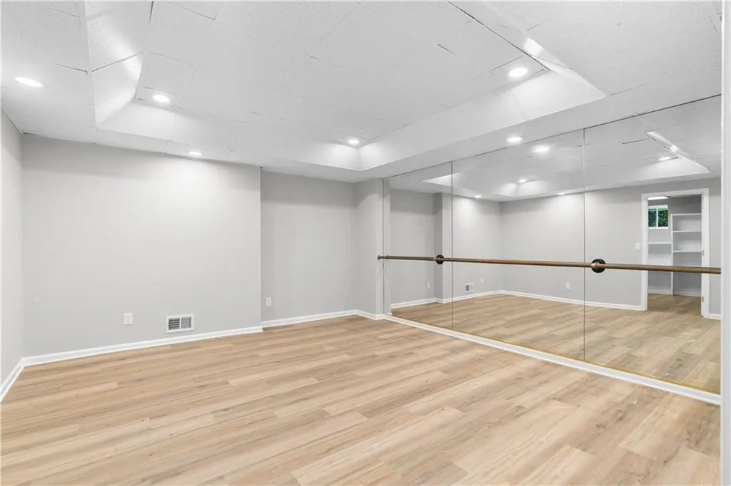 Finished below grade area with wood finished floors, a drop ceiling, and recessed lighting