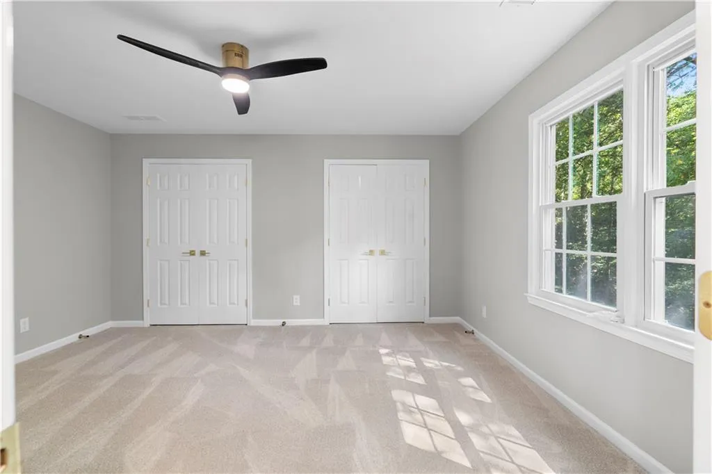 Unfurnished bedroom featuring two closets, light carpet, and a ceiling fan
