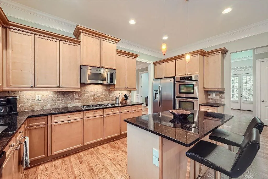 Kitchen featuring a center island, a kitchen breakfast bar, light hardwood / wood-style flooring, stainless steel appliances, and tasteful backsplash