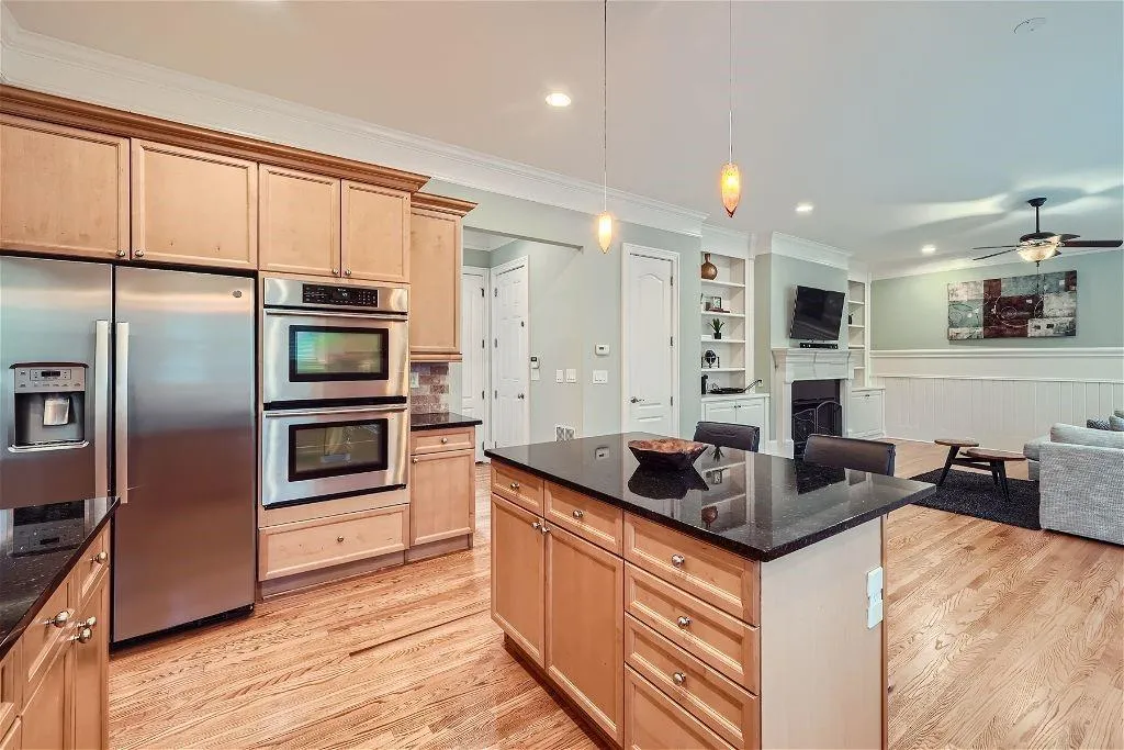 Kitchen with ceiling fan, light hardwood / wood-style floors, decorative light fixtures, and appliances with stainless steel finishes