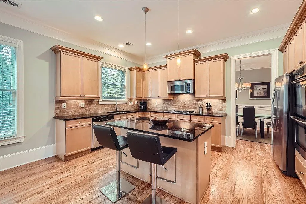 Kitchen featuring appliances with stainless steel finishes, a healthy amount of sunlight, a kitchen island, and light wood-type flooring