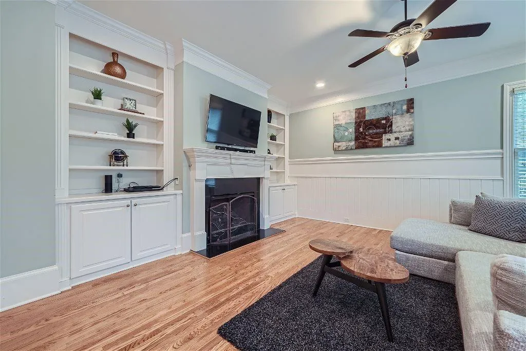 Living room featuring ceiling fan, ornamental molding, built in features, and light wood-type flooring