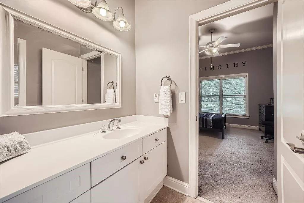 Bathroom featuring ornamental molding, large vanity, and ceiling fan
