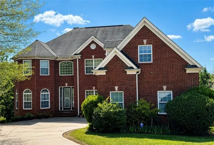 Brick exterior with white trim, multiple gables, and a prominent bay window