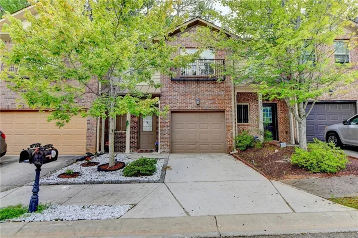 Traditional-style home featuring driveway, brick siding, a balcony, and an attached garage