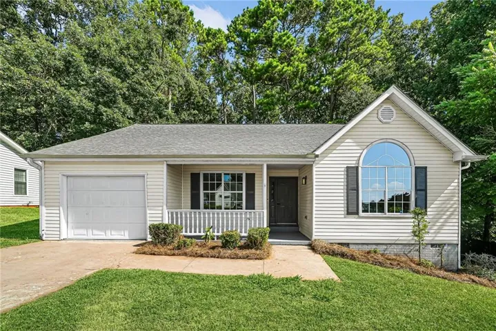 Single-story residence featuring light-toned siding, a covered front porch, an arched window, a one-car garage, and a manicured lawn