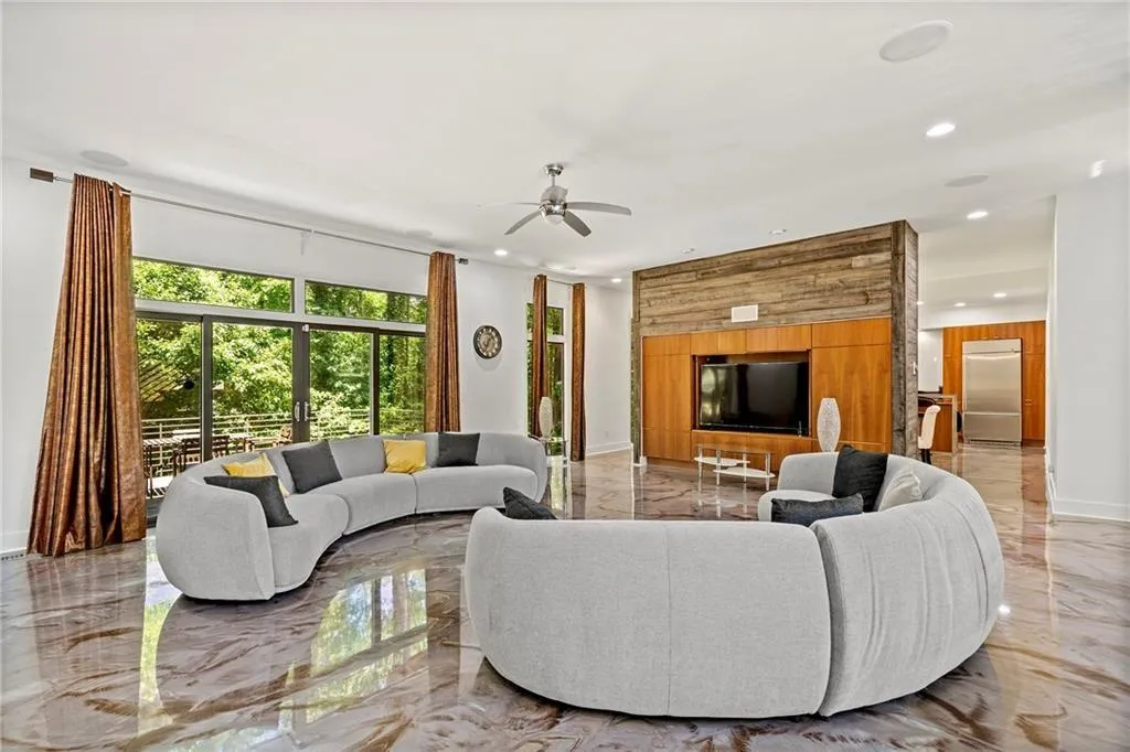 Living room with marble tiled floors, recessed lighting, wood walls, and ceiling fan