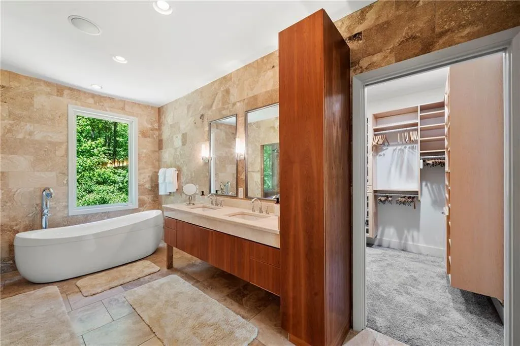 Bathroom with tile walls, a spacious closet, a freestanding tub, double vanity, and recessed lighting
