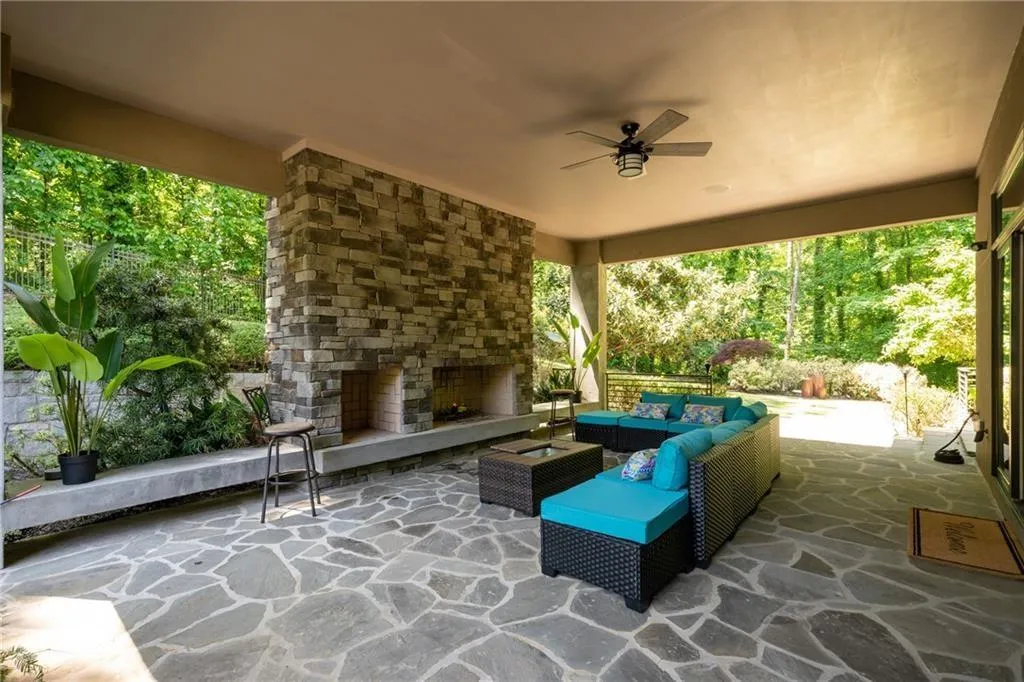 View of patio with an outdoor living space with a fireplace and ceiling fan