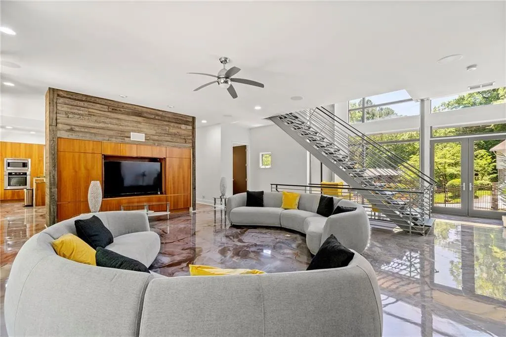 Living area with light marble finish flooring, expansive windows, stairway, recessed lighting, and wooden walls