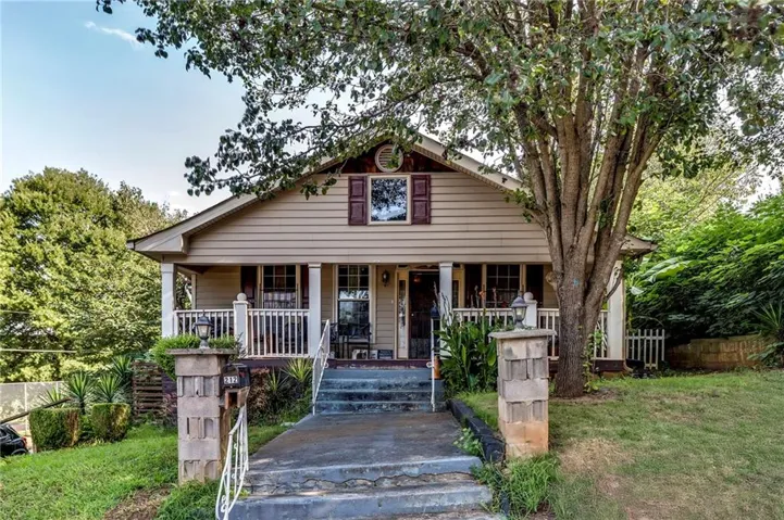 Gabled roofline with decorative gable vent, covered front porch, exterior siding, and front yard landscaping