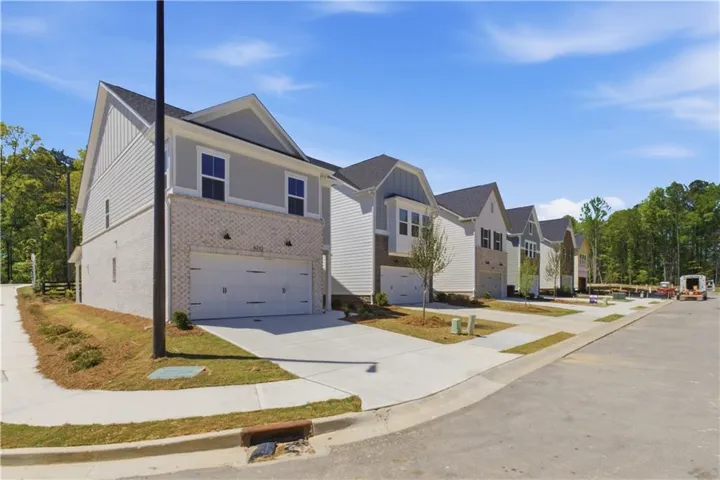 Contemporary townhome-style residences featuring light-colored brick veneer, horizontal siding, and prominent gabled roofs