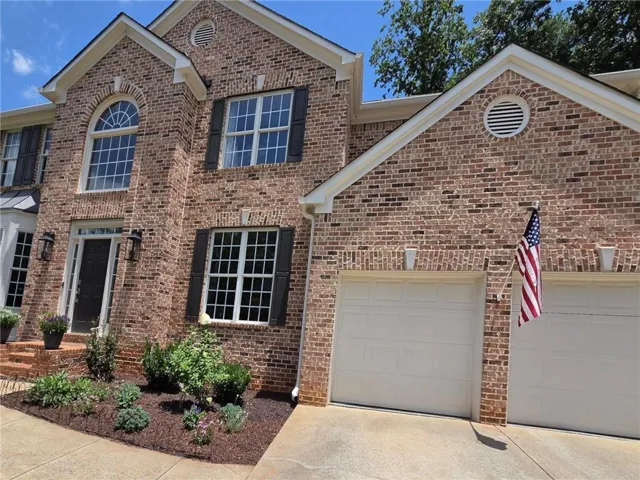 Brick exterior featuring a two-car garage with additional parking pad w/separate door to the garage.