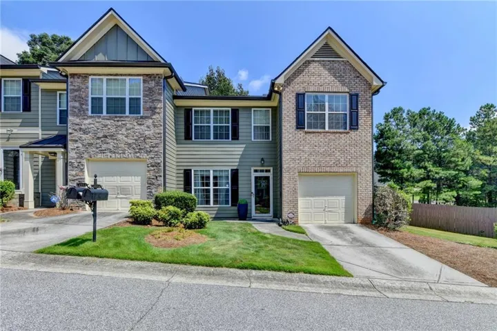 Exterior featuring a combination of brick and stone facade, private garage, and a well-maintained lawn