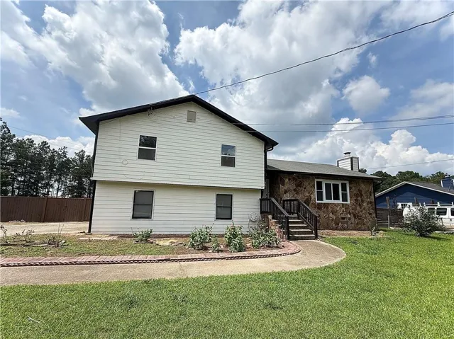 Exterior featuring mixed material siding, stone accents, a multi-level design, and a concrete pathway with brick edging