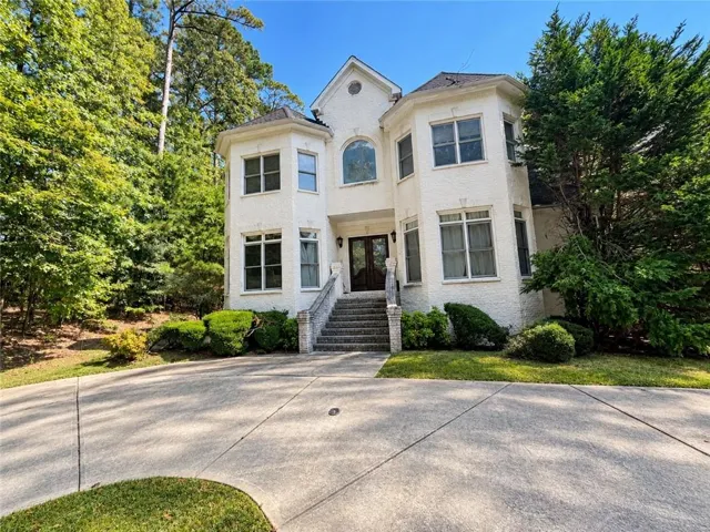 Stucco exterior with multiple bay windows, an arched entry, and a prominent front staircase