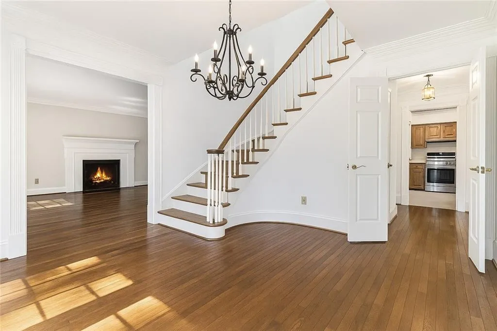 Virtual image showing updated foyer and stairs with wood flooring and new chandelier.