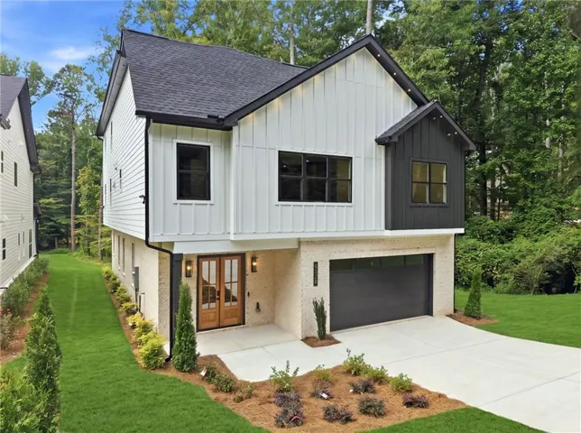 Contemporary exterior with white board and batten siding, black trim accents, a dark shingled roof, a two-car garage, and a light brick lower level