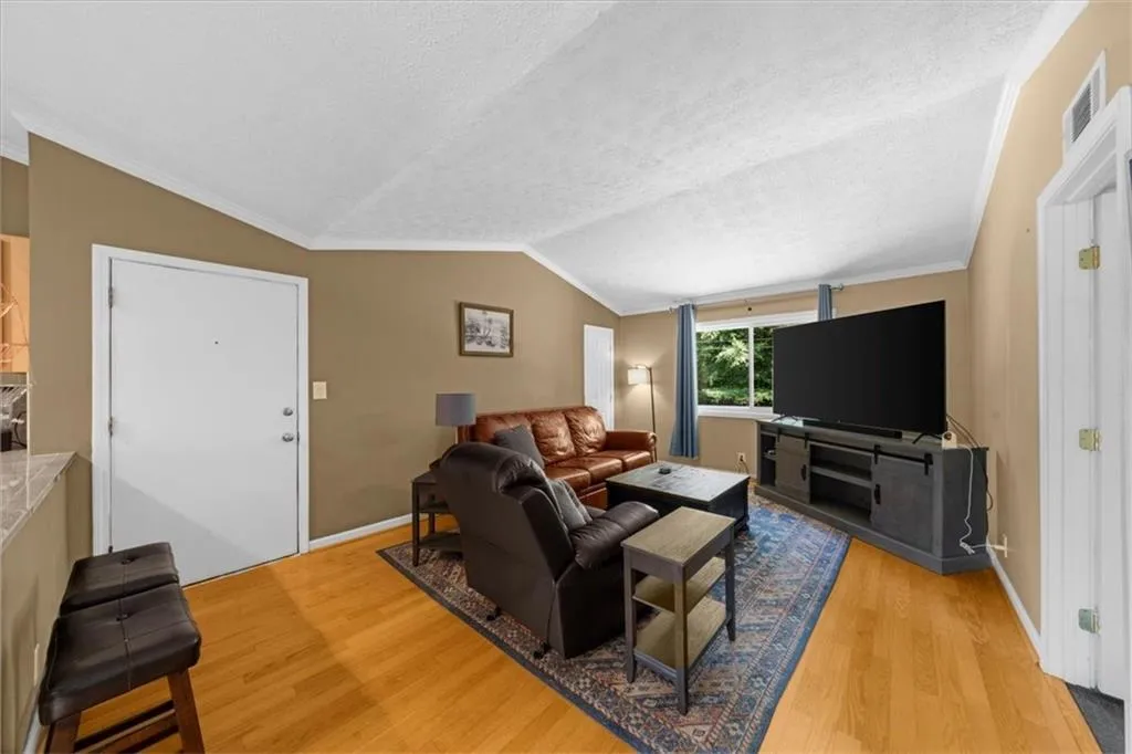 Living area featuring light wood finished floors, lofted ceiling, and crown molding